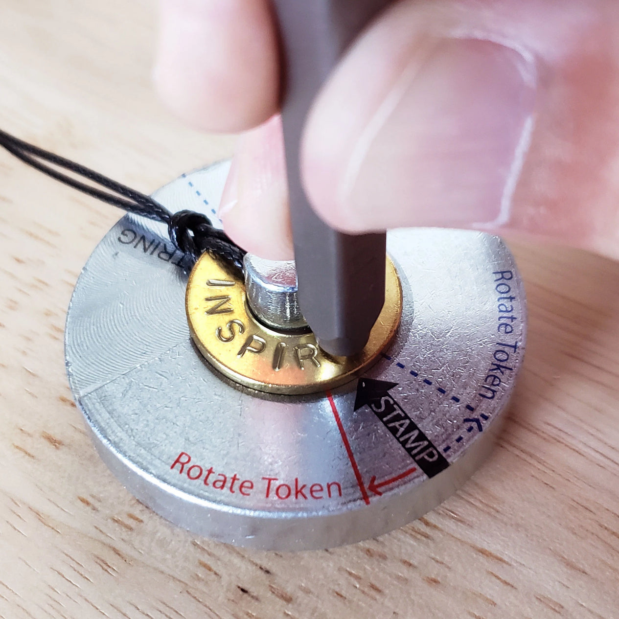Person stamping the word INSPIRE on their classic bracelet which is placed on a metal stamping base