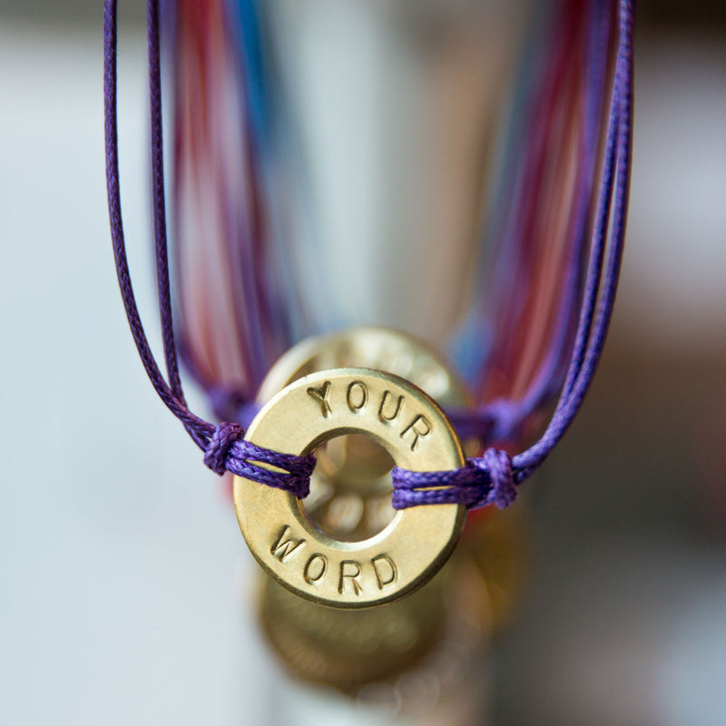 A close-up of MyIntent Custom Classic Bracelet Purple String with Brass Token
