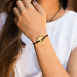 Girl wearing MyIntent Custom Twist black string Bracelet Gold token with word IMPACT