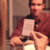 A woman reading a question from a MyIntent Question card at the dinner table 