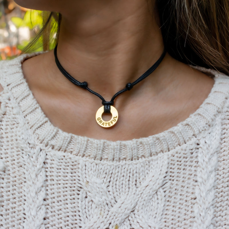 A girl wearing her MyIntent Custom Adjustable Black Necklace with Gold Token with the word GRATEFUL