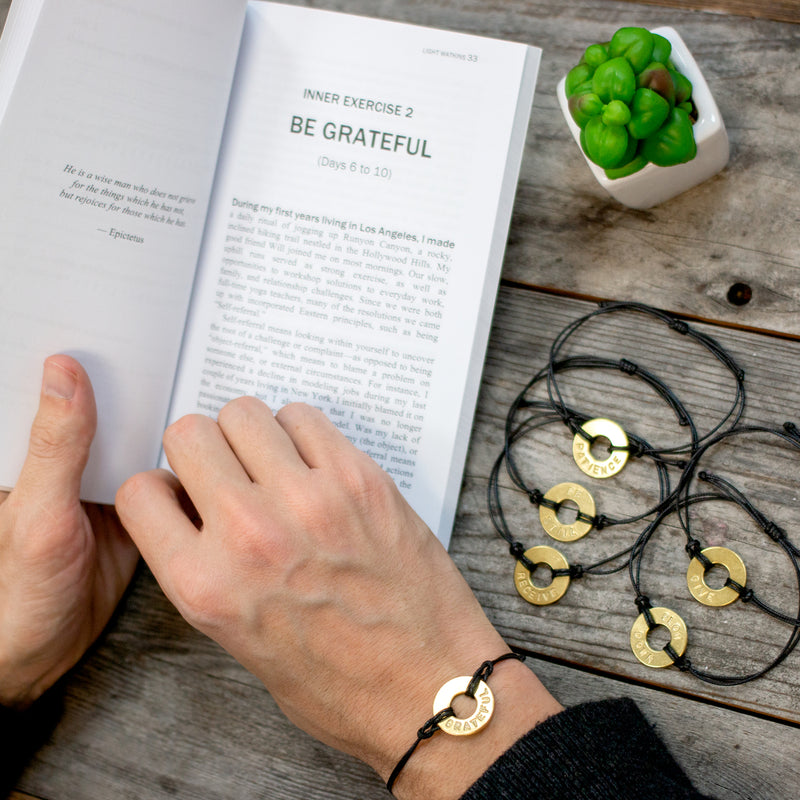A person reading The Inner Gym book while wearing their MyIntent classic black bracelet
