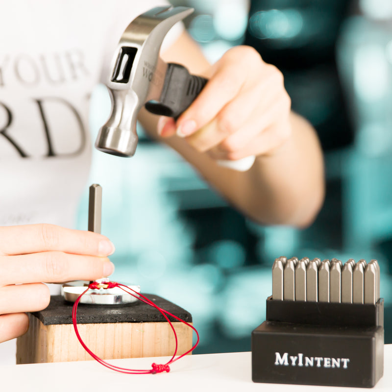 Someone stamping a classic red bracelet by using their MyIntent Maker Kit