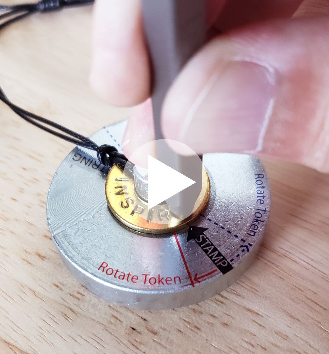 Person stamping the word INSPIRE on their classic bracelet which is placed on a metal stamping base