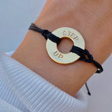 Person wearing MyIntent Custom Twist Bracelet Black String Gold Plated Token with the words STEP UP