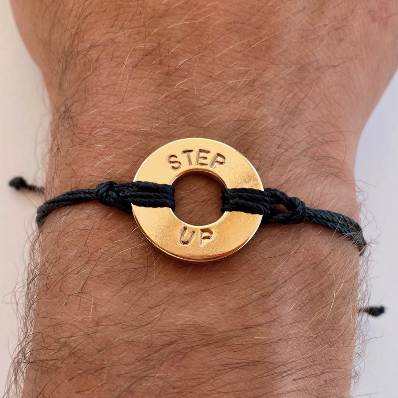 Person wearing MyIntent Custom Twist Bracelet Black String Gold Plated Token with the words STEP UP