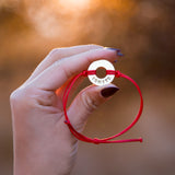 Person holding their MyIntent Custom Classic Bracelet Red String Nickel Token with word IGNITE